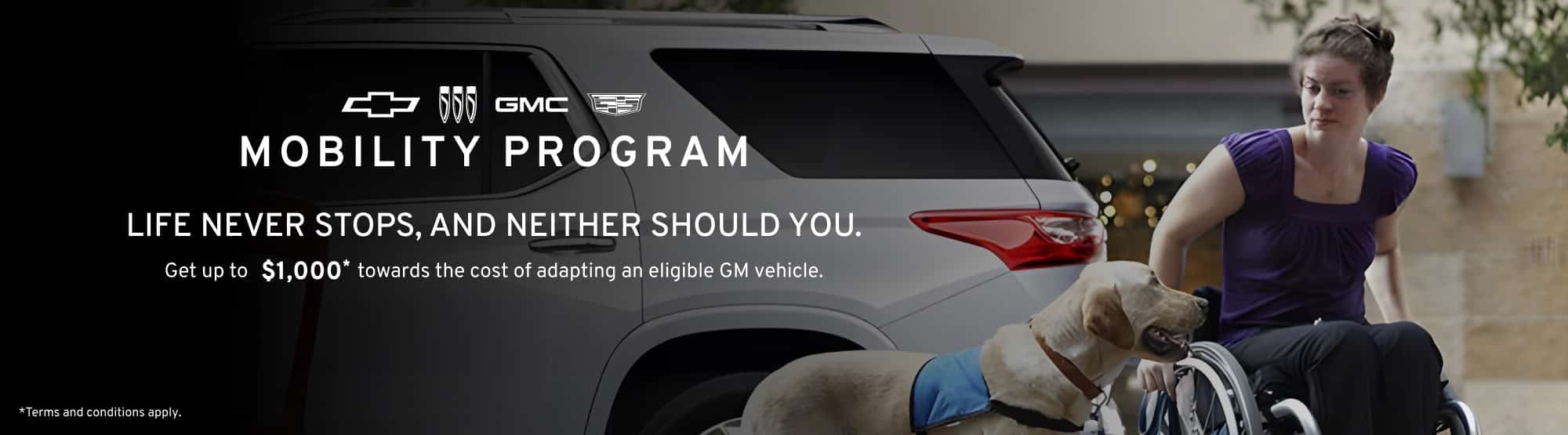 GM Mobility Program: Woman in wheelchair with service dog beside a vehicle, highlighting accessibility.
