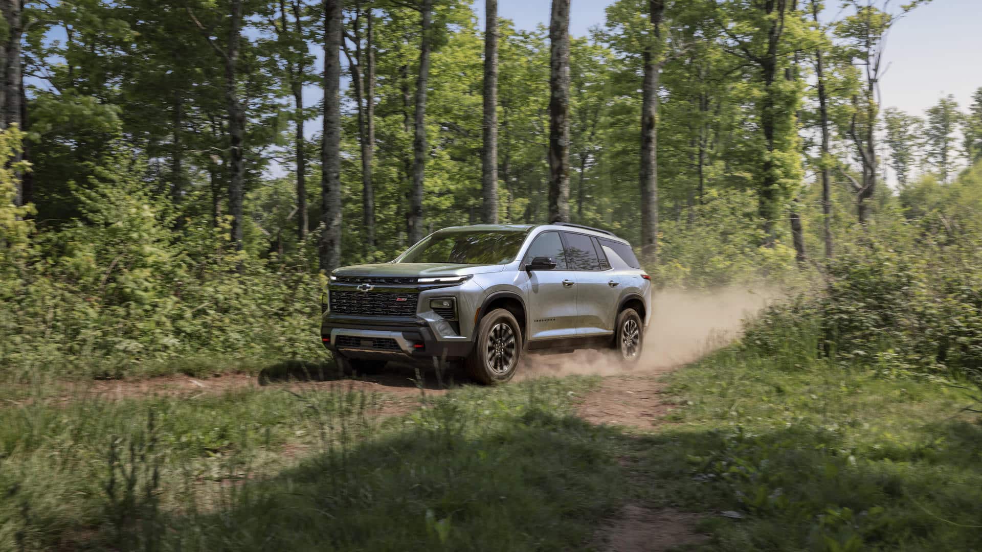 A red SUV with black and chrome accents is driving on a city street. Its a four-door vehicle with large alloy wheels, a sleek design, and tinted windows. The background features blurred buildings and trees.