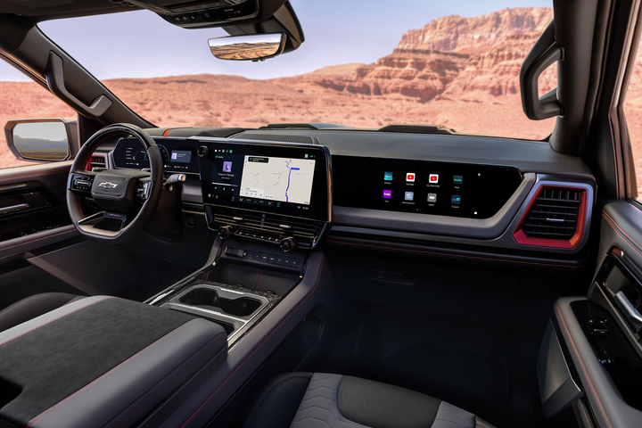 The image shows the interior of a modern car, featuring a steering wheel, a digital dashboard, and a large touchscreen display on the center console. The display shows various controls and settings. The car has a sleek, black design.