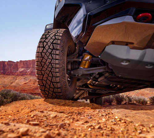 Off-road vehicle navigating rocky desert terrain under a clear blue sky.