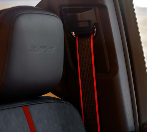Car seat with "ZR2" logo, featuring a red-striped seatbelt, highlighting style and safety.