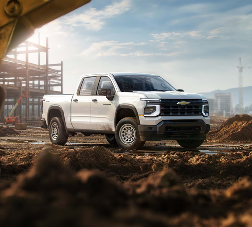 White pickup truck at a construction site with building framework and mountains in the background.