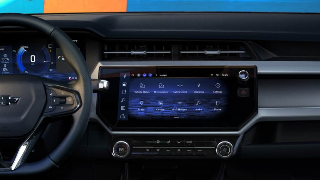 A person in light pants and black shoes uses a foot motion to open the rear hatch of a red Chevrolet Blazer RS, showcasing the hands-free feature. Theyre also carrying a black bag in their right hand.