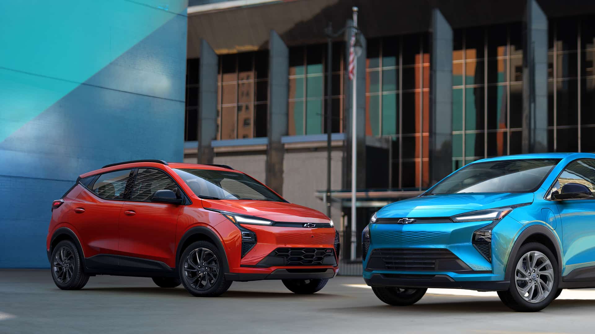 Red and blue Chevrolet SUVs parked in an urban setting with modern architecture.