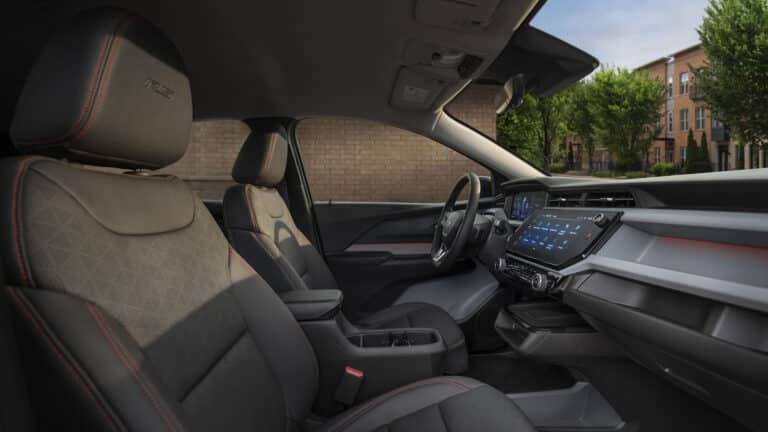 Modern car interior with sleek dashboard, digital display, and plush seats, set against a street view.