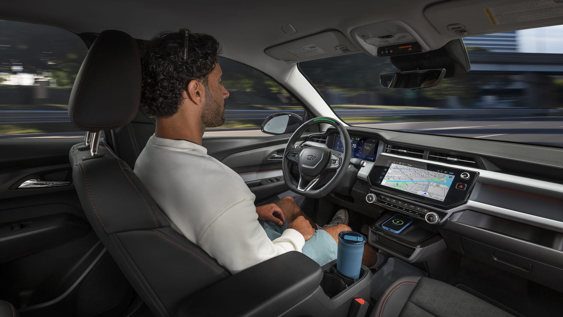 Man seated in a car using autonomous driving features; dashboard displays a map.