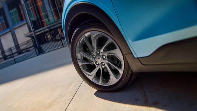 Close-up of a blue car's wheel on a concrete surface, showcasing sleek tire design.