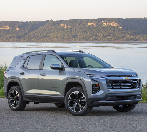 Silver SUV parked by a scenic waterfront with hills in the background, displaying modern design.