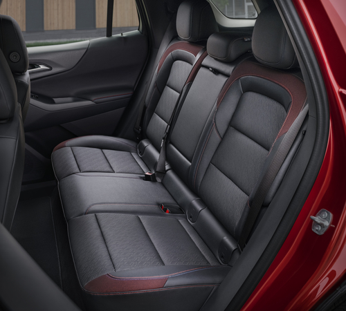 Back seat of a car with dark leather upholstery and red accents, showcasing modern design.