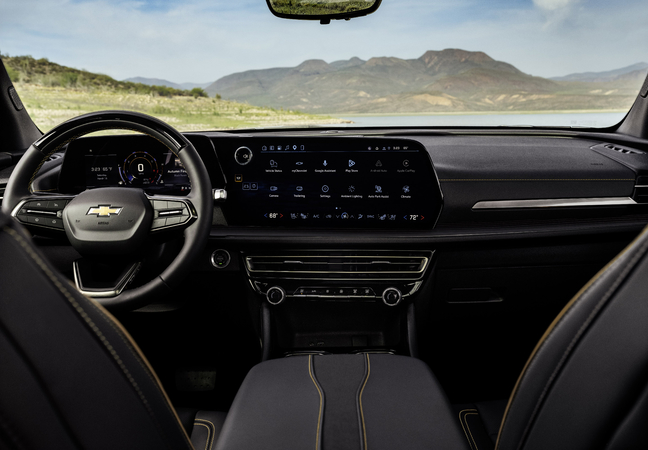 Modern car interior with digital dashboard and large touchscreen display, overlooking scenic mountains.