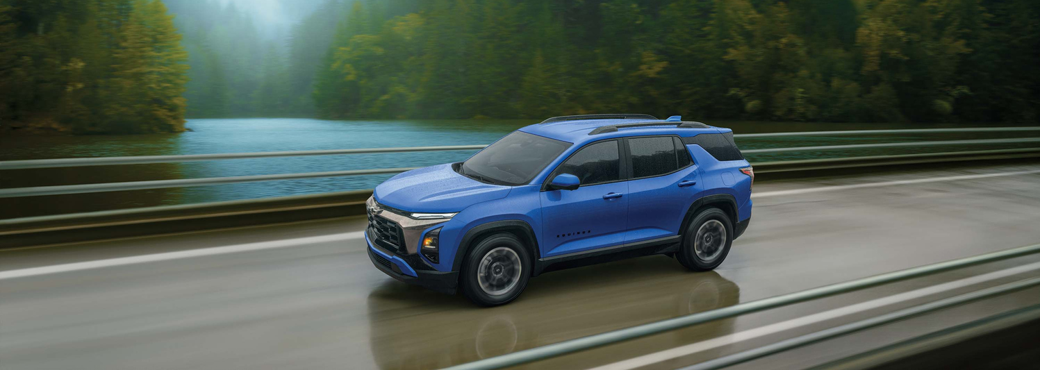 A red SUV with black and chrome accents is driving on a city street. Its a four-door vehicle with large alloy wheels, a sleek design, and tinted windows. The background features blurred buildings and trees.